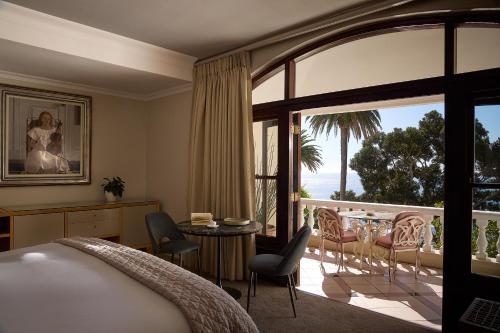 a bedroom with a bed and a balcony with a table and chairs at Ellerman House in Cape Town