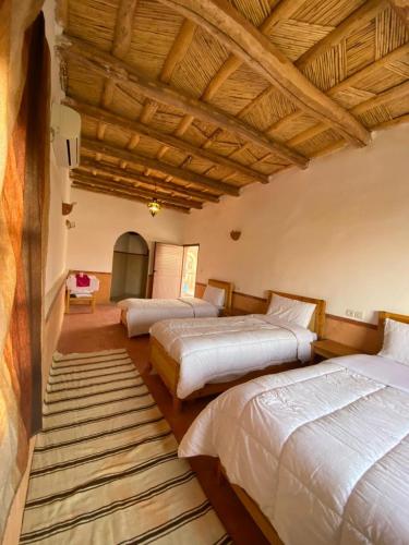 a bedroom with two beds and a large wooden ceiling at Hôtel bleu ciel in Aït Yous