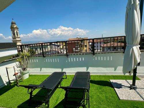 a balcony with chairs and an umbrella and a clock tower at Catullo Loft Near Verona in Dossobuono