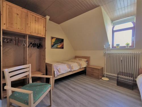 a bedroom with a bed and a chair and a window at Familie Hensen - FeWo mit überdachter Terrasse im Ortskern von Tarp in Tarp