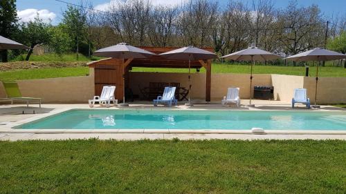 a swimming pool with chairs and umbrellas at La truffière in Belvès