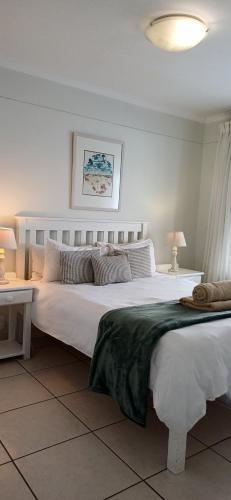 a bedroom with a large white bed and two tables at Point Village Accommodation - Alista in Mossel Bay