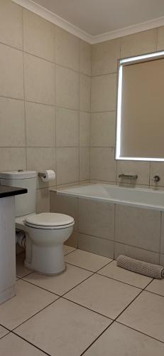 a bathroom with a toilet and a tub and a sink at Point Village Accommodation - Alista in Mossel Bay