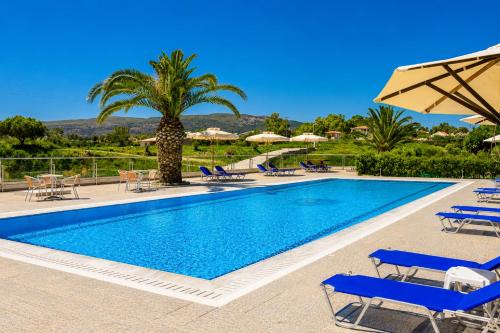 a pool with chairs and umbrellas and a palm tree at Nautilos Hotel in Soullároi