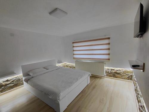 a white bedroom with a bed and a window at Apartment Matej in Kruševo