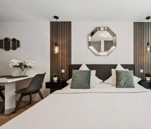 a bedroom with a bed and a desk and a mirror at Prime Host Sophie Apartments in Karlsruhe