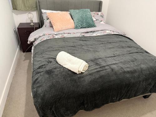 a bed with a black blanket and some pillows at Aries de Baldock in Canterbury