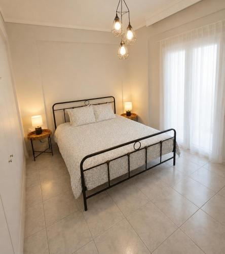 a bedroom with a bed with two tables and two lamps at Elenis Garden View Apartment in Perea