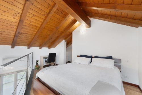 a bedroom with a white bed and wooden ceilings at La Casa Di Lillo - Angera in Angera