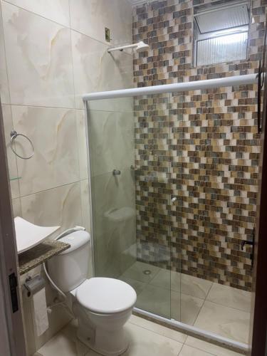 a bathroom with a toilet and a glass shower at Casa espaçosa em Itacimirim com piscina e churrasqueira! in Camaçari