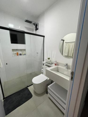 a white bathroom with a toilet and a sink at Apartamento Tranquilo e Aconchegante in Carmo do Rio Claro