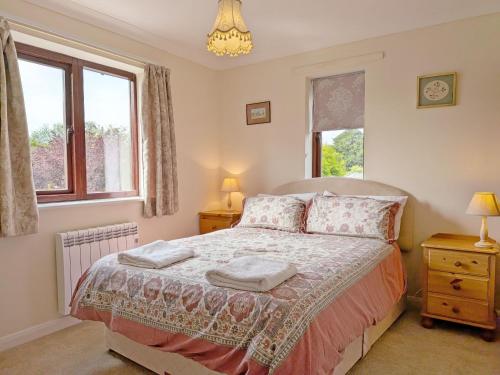 a bedroom with a bed and two windows at Bramley Cottage in Charlton