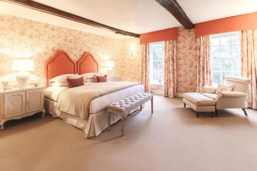 a bedroom with a large bed and a chair at Ormesby Manor House & The Shepherds Huts & Well Lodge in Ormesby Saint Michael
