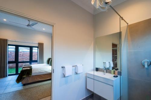 a bathroom with a shower and a sink and a bed at The Pods Victoria Falls in Victoria Falls