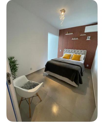 a bedroom with a large bed and a chair at Apartamento Tranquilo e Aconchegante in Carmo do Rio Claro