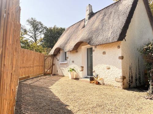 a small white cottage with a thatched roof at La Chaumière des Marais Escapade romantique & jacuzzi privatif in La Chapelle-des-Marais