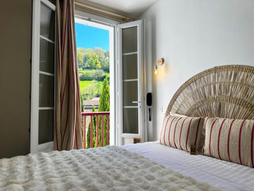 ein Schlafzimmer mit Bett und Tür zum Balkon in der Unterkunft Hôtel Juantorena in Saint-Étienne-de-Baïgorry