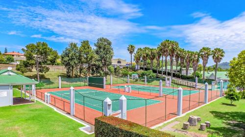 a tennis court in a park with palm trees at Riverclub Villas in Plettenberg Bay