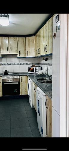 a kitchen with white appliances and wooden cabinets at Pisos Baraja Gl in Madrid