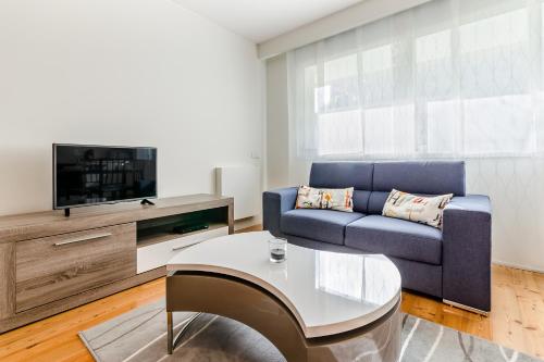 a living room with a blue couch and a tv at RS Porto Boavista Studios in Porto