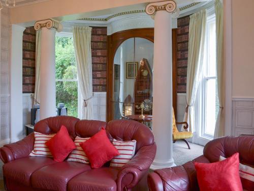 a living room with a brown leather couch with red pillows at Foulston Apt- Cv12 in Liskeard