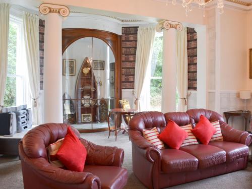 a living room with two leather couches with red pillows at Foulston Apt- Cv12 in Liskeard