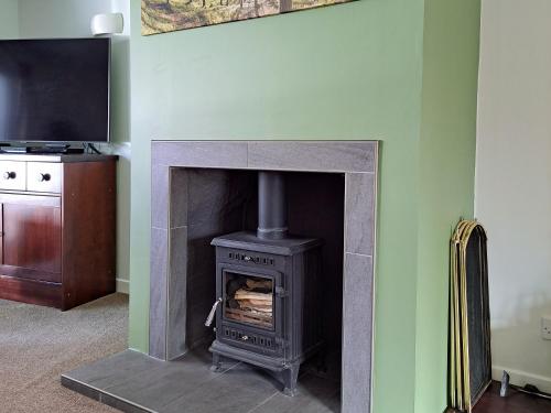 a fireplace with a stove in a room at Tall Pines in Carrbridge