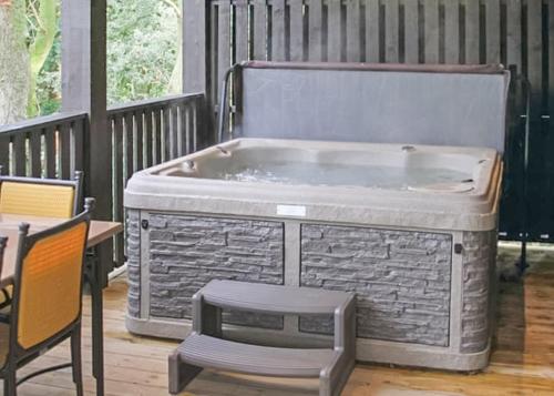a hot tub sitting on a porch with a chair at Brockwood Hall Lodges in Silecroft