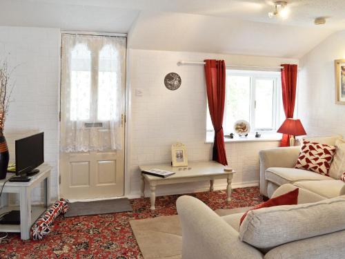 a living room with a couch and a tv at Gamekeepers Apt - Cv20 in Liskeard