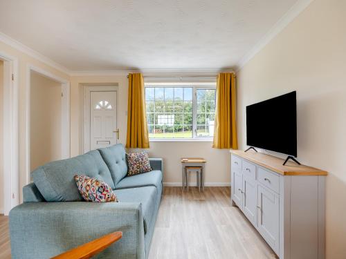 a living room with a blue couch and a flat screen tv at Oaks - Uk47372 in Burgh le Marsh