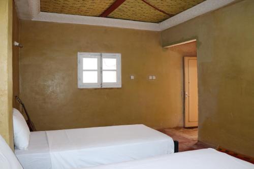 two beds in a room with a window at Kol izem in Ksar el Kbir
