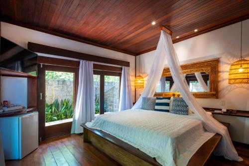 a bedroom with a canopy bed and a window at Sombra e Água Fresca Resort in Pipa