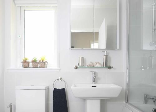 a white bathroom with a sink and a mirror at Clear Sky Lodge Park in Kielder