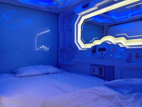 a bed in a room with a blue light at TRIVPODS Capsule Hotel in Trivandrum