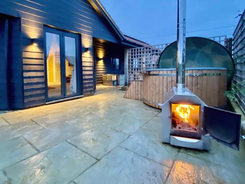a fireplace on a patio next to a house at Moor Farm Lodge in Bawdeswell