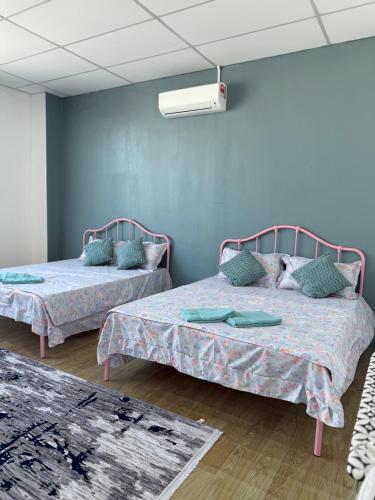 two beds in a room with blue walls at Tido Cottage in Macang
