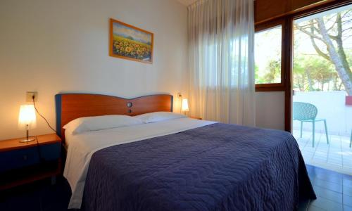 a bedroom with a bed with a blue blanket and a window at Villaggio Marina in Bibione