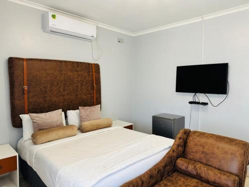 a bedroom with a bed and a chair and a television at Kim Guesthouse in Harare