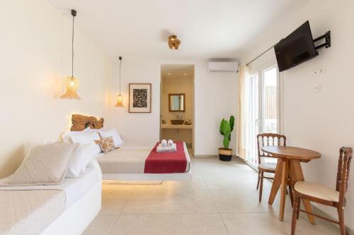 a bedroom with a bed and a table and a tv at Casa Philippi Suites in Mikonos