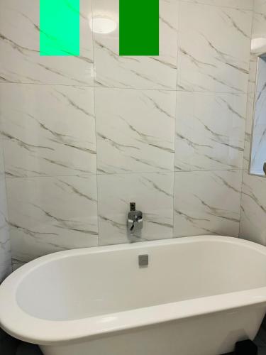 a white bath tub in a bathroom with a green box at Kim Guesthouse in Harare