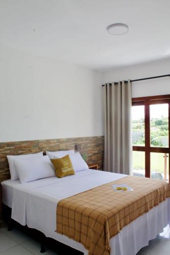 a bedroom with a large white bed with a window at Apartamentos Recanto do Rouxinol em Serra de São Bento RN in Serra de São Bento