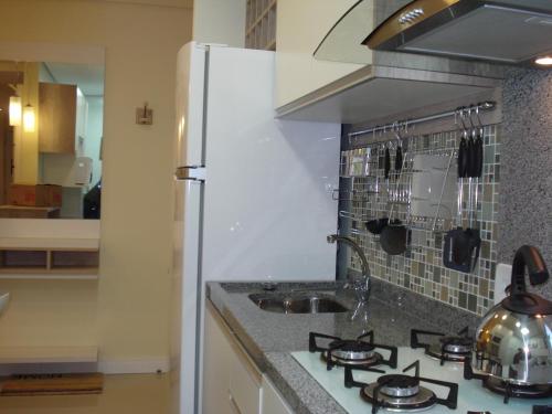 a kitchen with a stove and a white refrigerator at Apartamento Aeroporto in Porto Alegre