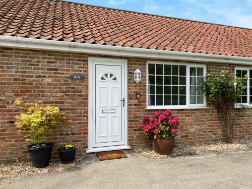 a brick house with a white door and flowers at Ivy - Uk47373 in Burgh le Marsh
