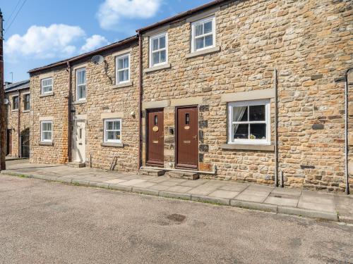 a brick building with brown doors on a street at Squirrel Cottage - Uk37886 in Stanhope