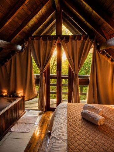 a bedroom with a bed and a large window at Cabanas dos Plátanos in Gramado
