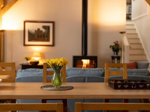a dining room table with a vase of flowers on it at Hatchers Barn - Uk42080 in East Garston