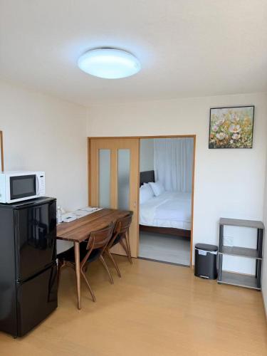 ein Zimmer mit einem Tisch und ein Schlafzimmer mit einem Bett in der Unterkunft MUTSUMI Hotel in Saga