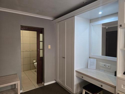 a bathroom with a sink and a television and a toilet at Bayside Guesthouse in Port Elizabeth