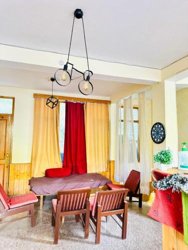 a bedroom with a bed with red and yellow curtains at Negi Wooden House in Manāli