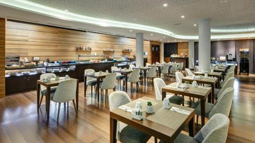 a restaurant with tables and chairs and a kitchen at Sercotel Coliseo in Bilbao